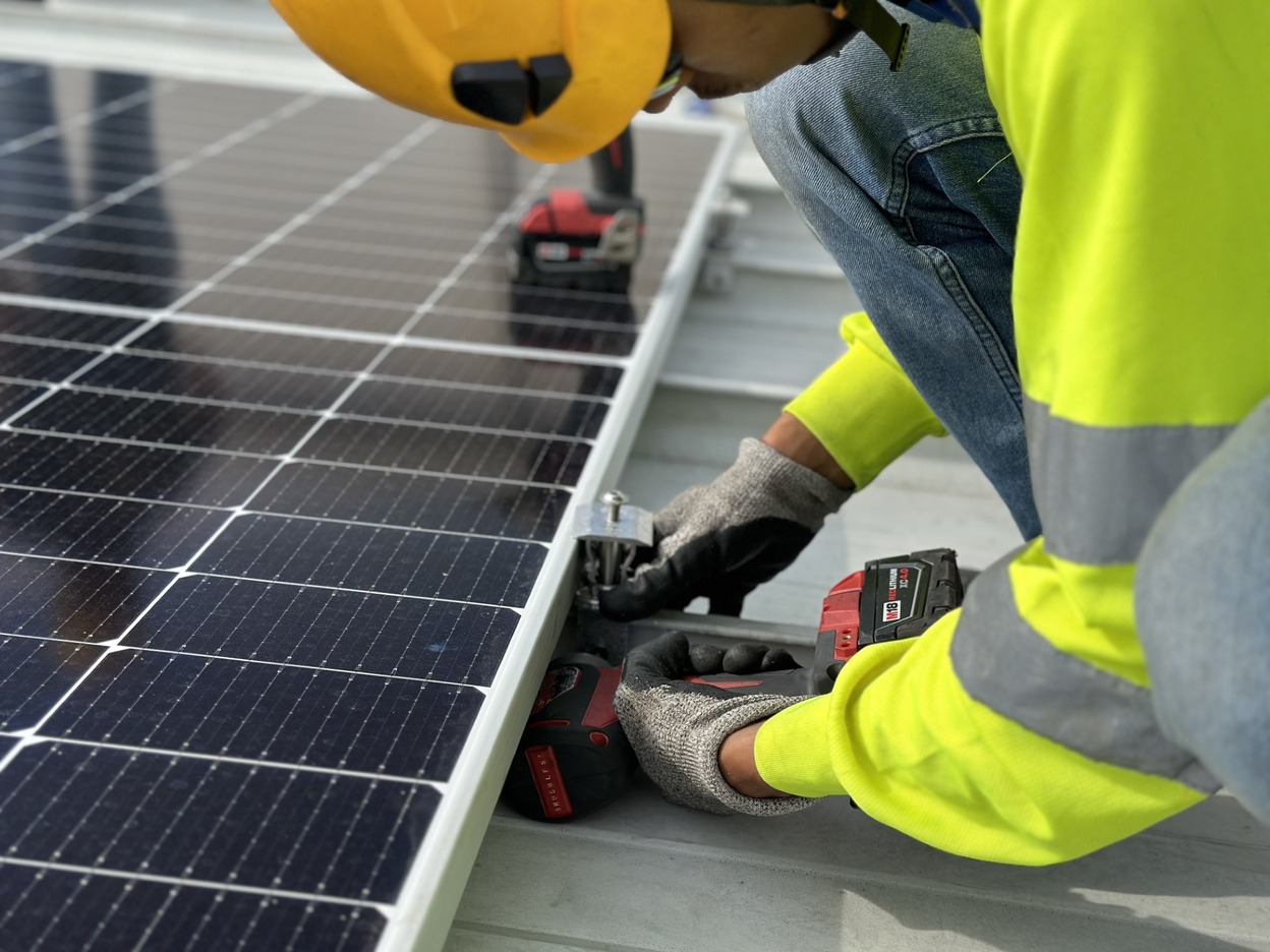Worker installing a solar panel on a roof
